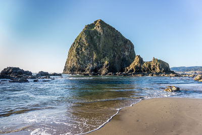 Rock formation on beach against clear blue sky