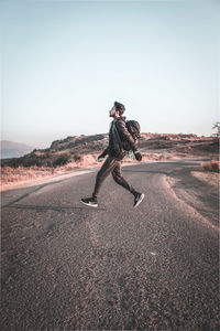 Man levitating over road against clear sky