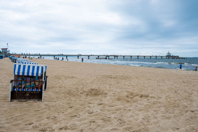 Hooded chairs on beach against sky