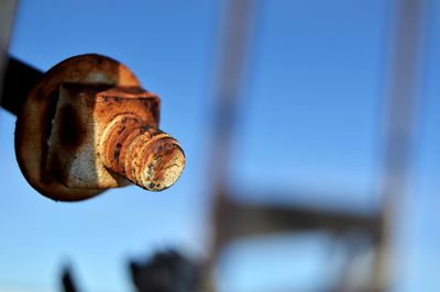 Close-up of rusty bolt against blue sky