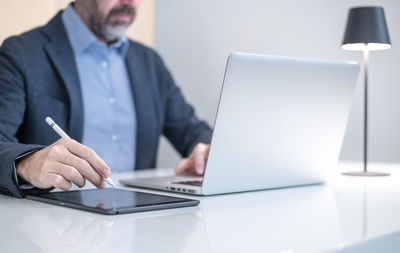 Midsection of businessman using laptop at office