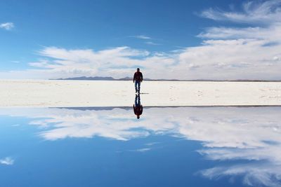 Rear view of woman with arms raised against sky