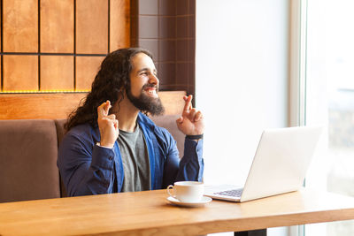 Young man using mobile phone while sitting on table