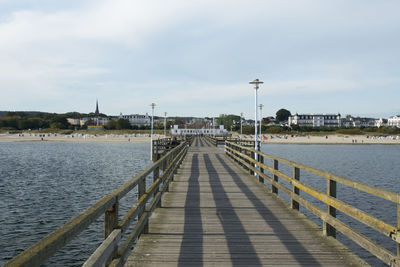 Empty pier over sea against sky