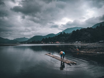 Man on boat in lake against sky