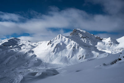 Scenic view of snow covered mountains against cloudy sky