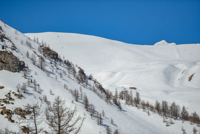 Scenic view of snow covered mountains against clear blue sky