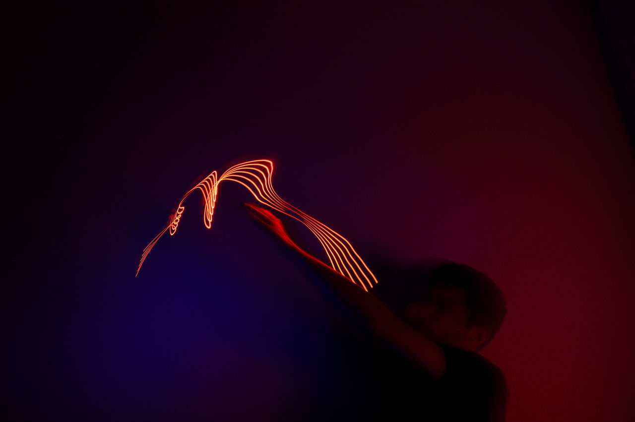 copy space, one person, red, illuminated, long exposure, motion, indoors, studio shot, glowing, close-up, hand, human hand, leisure activity, light painting, lifestyles, night, low angle view, cut out, blurred motion, black background