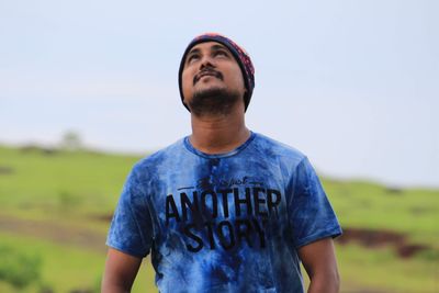 Man looking up while standing against sky