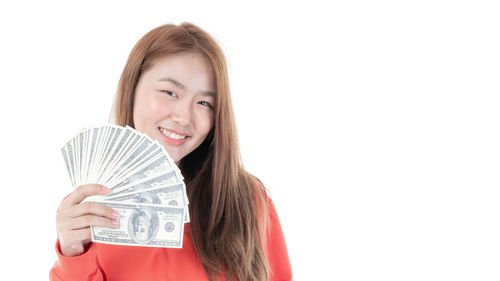 Portrait of a smiling young woman holding camera against white background