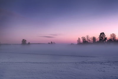 Scenic view of snow covered landscape against sky at sunset