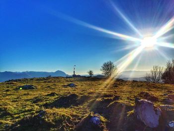 Scenic view of landscape against blue sky on sunny day