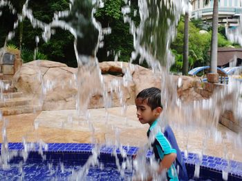 Boy standing by waterfall