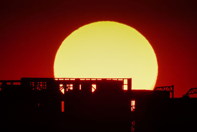 Silhouette built structure against orange sky