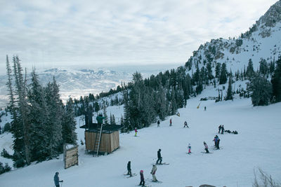 People skiing on snow covered land against sky