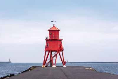 Lighthouse by sea against sky