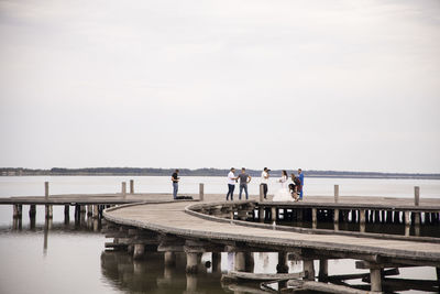 People on pier over sea against sky