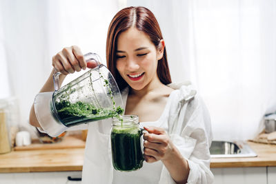 Young woman holding juice in kitchen