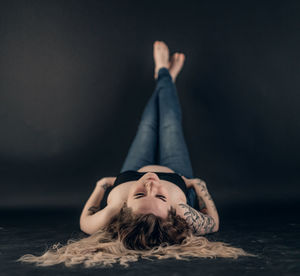 Low section of woman sitting on sand at home