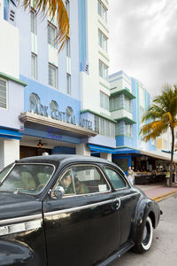 Cars on road by building in city against sky