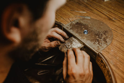 Jeweler holding unfinished ring in dirty hands and checking quality in workshop