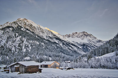 Snow covered landscape and houses against sky