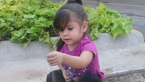 Cute girl looking down while holding leaf