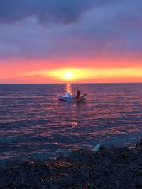 Scenic view of sea against cloudy sky during sunset