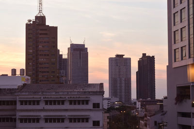 Modern buildings in city against sky during sunset