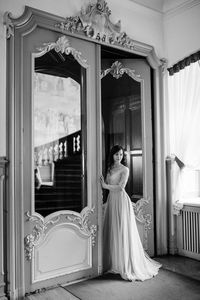 Woman looking away while standing against door of building