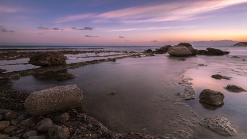Rocks on beach against sky during sunset