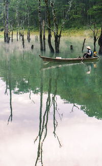 Man boating on lake in forest