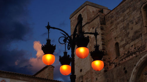 Low angle view of illuminated street light by castle against sky at dusk