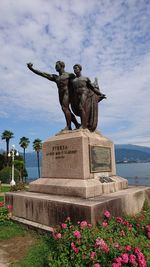 Statue of flowering plant against cloudy sky