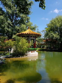 Gazebo by lake in park against sky