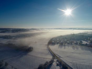 Scenic view of snow covered landscape against bright sun