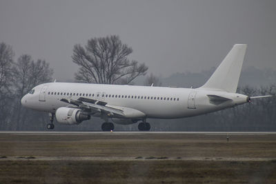 Airplane flying over airport runway against sky