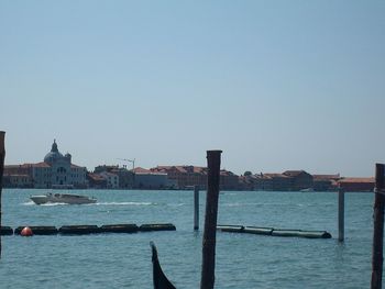 Boats in calm sea against clear sky