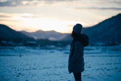 Side view of woman standing on snowcapped field