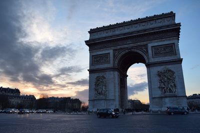 Arc de triomphe by road against sky during sunset in city