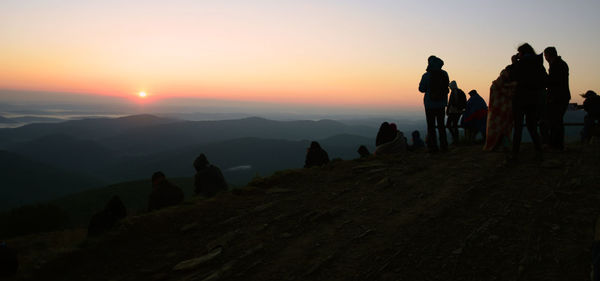 Silhouette people on mountain against sky during sunset