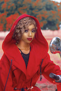 Portrait of beautiful young woman wearing red hoodie sitting on motorcycle