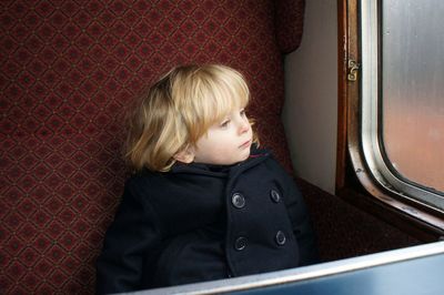 Child sitting on seat by window in train