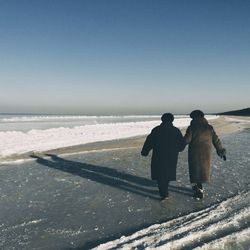 Rear view of couple walking on beach