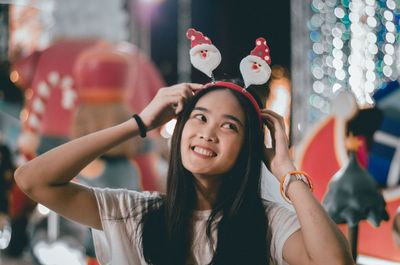 Smiling young woman looking away at night during christmas