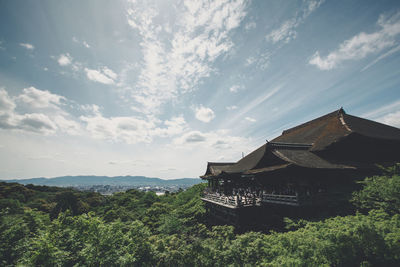 House amidst trees and buildings against sky