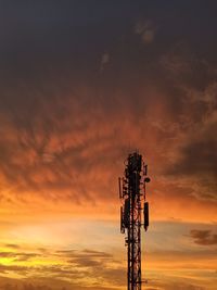 Low angle view of electricity pylon against sky during sunset