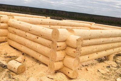 Stack of logs on field against sky