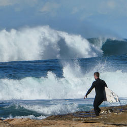Man surfing on sea against sky