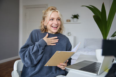 Portrait of young woman using laptop at home